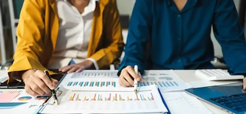 Two people sit at a desk reviewing charts and graphs on paper, with one holding a pen and the other using a calculator. Traffic Consultants, Inc. (TCI)